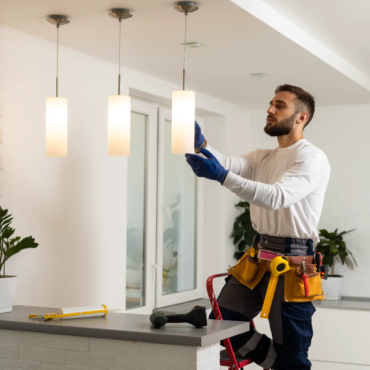construction worker installing pendant lights over a half wall in house