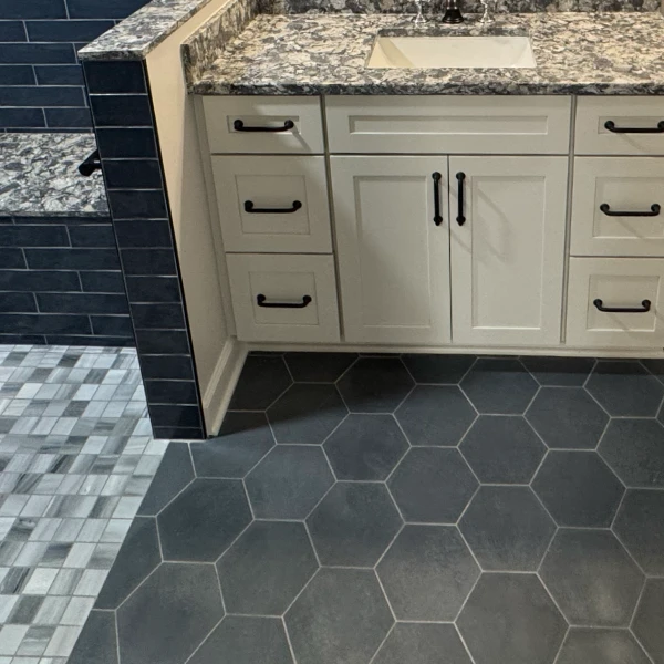 hexagon tile on bathroom floor in front of vanity and small square tile in shower