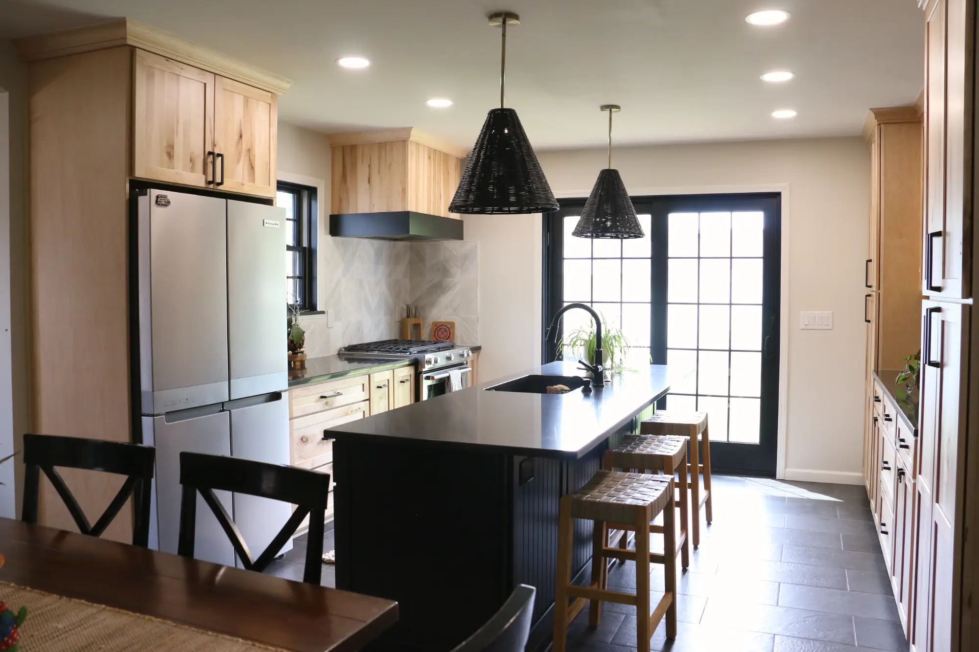 A modern kitchen with contrasting dark and light wood cabinets. A large french door in the background.
