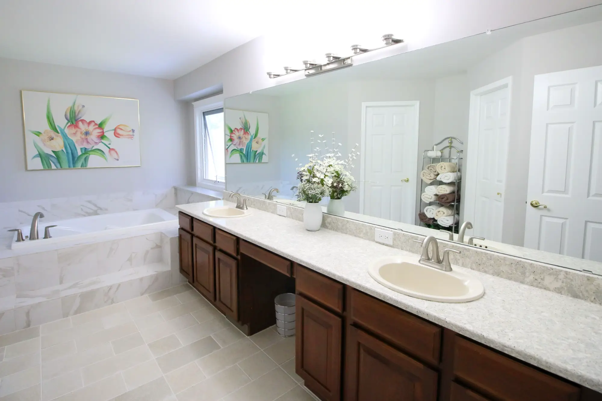 A remodeled bathroom with two sinks and medium wood tone cabinets.