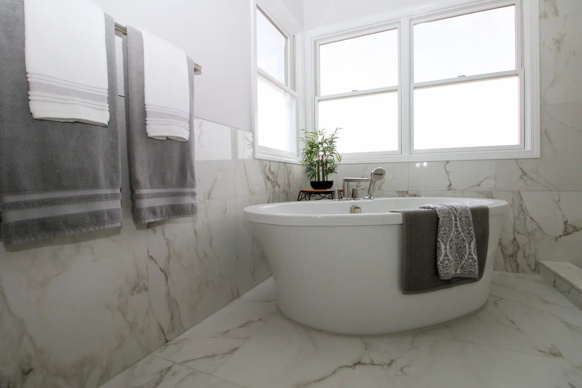 A remodeled bathroom with a spa bath tub and marble tile.
