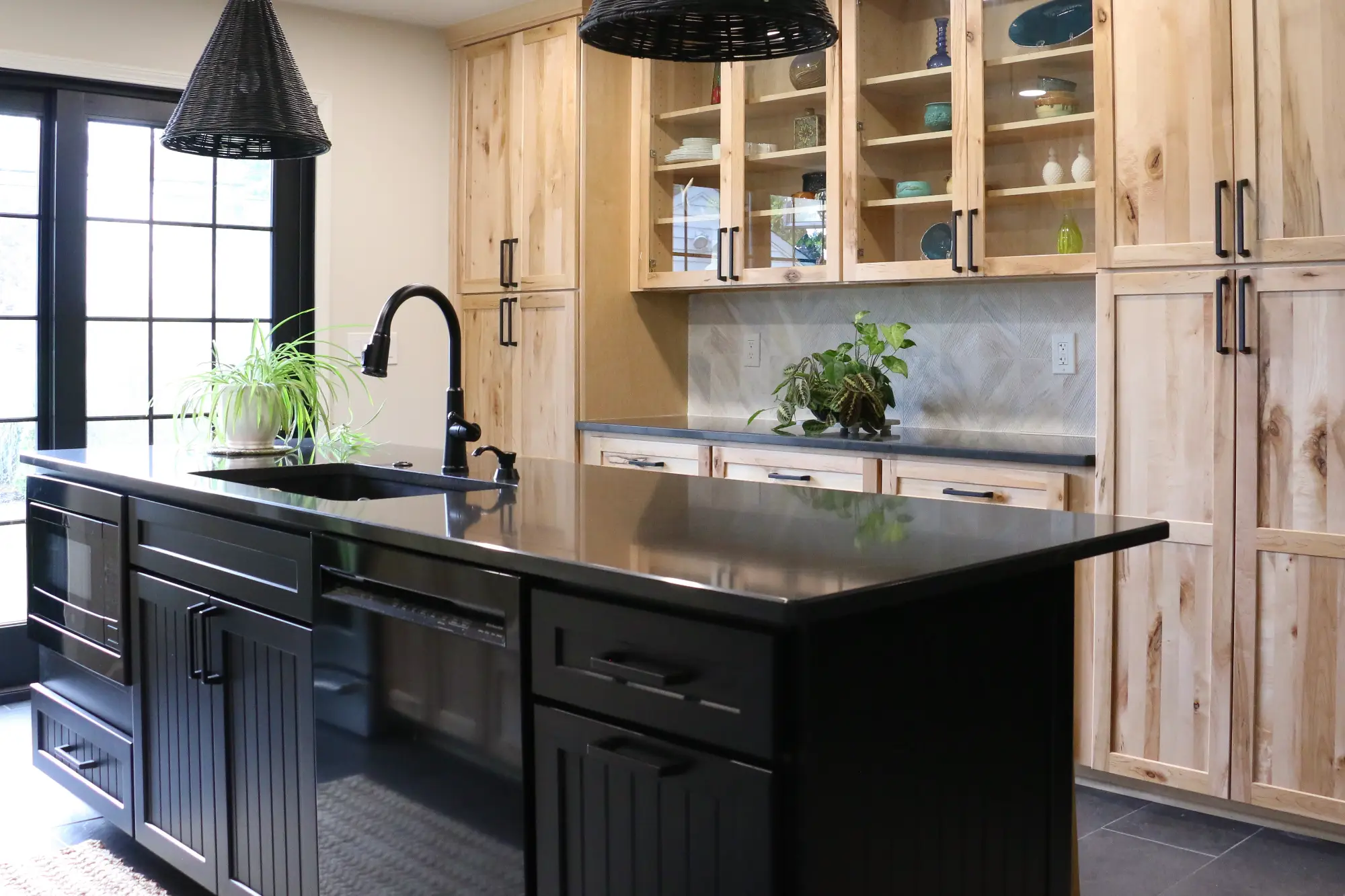 Modern kitchen redesign with dark island cabinets and light wood color wall cabinets.