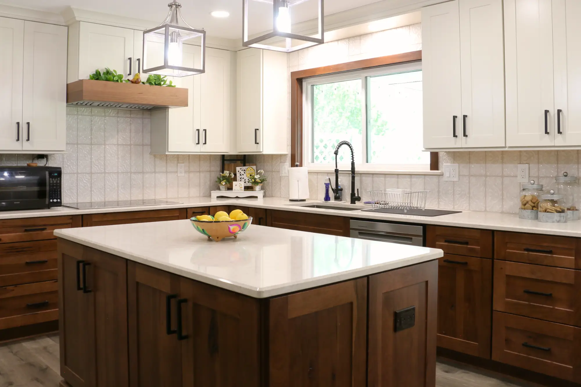A modern kitchen redesign with medium tone and white wood cabinets and white stone countertops.
